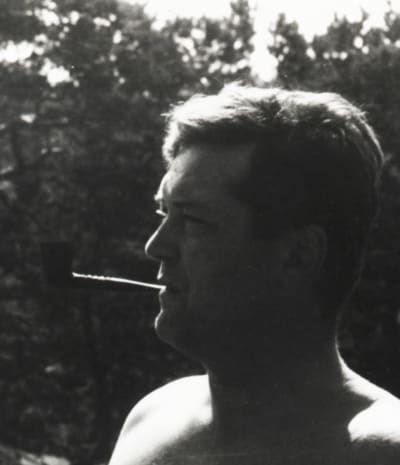 svartvitt foto taget utomhus av en man i profil med en lång cigarett i munnen