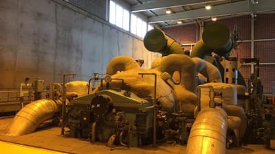 Den gamla delen av anläggningarna vid Vaskiluodon Voima. Inne i fabriksbyggnad, rör och maskiner.