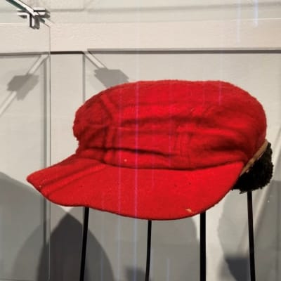 Punainen lakki näyttelyvitriinissä.