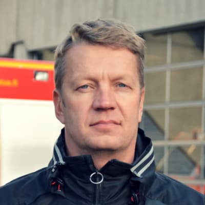 Knut Lehtinen framför en brandbil som står parkerad framför pargas brandstation.
