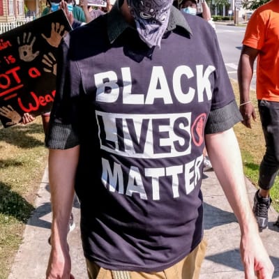 Mies osoittaa mieltä päällään Black Lives Matter -paita.