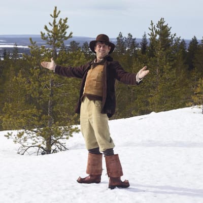 Marko Syysmaan esittämä Nätti-Jussi seisoo Ounasvaaran lumisissa maisemissa.