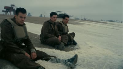Soldaterna Alex (Harry Styles), Gibson (Aneurin Barnard) och Tommy (Fionn Whitehead) sitter på stranden i Dunkirk och låter vågorna skölja över dem.