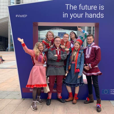 Suomen saamelaisnuorten delegaatio Brysselissä kyltin edessä, jossa lukee VisitEP ja The Future is in your hands.