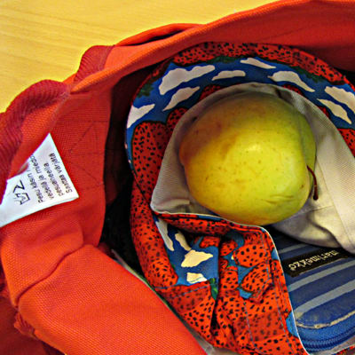 Naisen käsilaukusta voi löytyä muun muassa kurkkupastilleja, hattu ja omena.