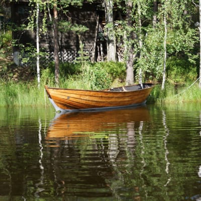 A wooden rowboat at a summer cottage