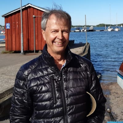 En man som står i en hamn bredvid en båt. 