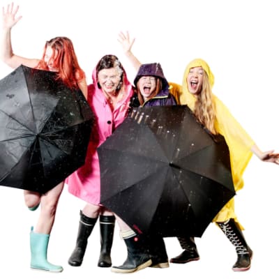 Kuvassa neljä naista seisoo sateenvarjon kanssa.