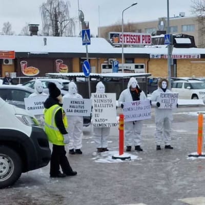 Valkohaalareihin pukeutuneita mielenosoittajia kylttien kanssa Korson suurmarkkinoilla, Vantaalla 25.3.2023.