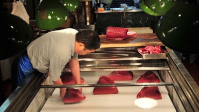 Japansk man lägger om fiskbitar på Tokyos fiskmarknad