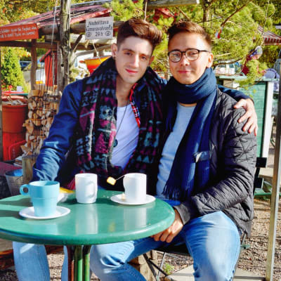 José och Sami dricker kaffe utomhus vid ett kafé. 