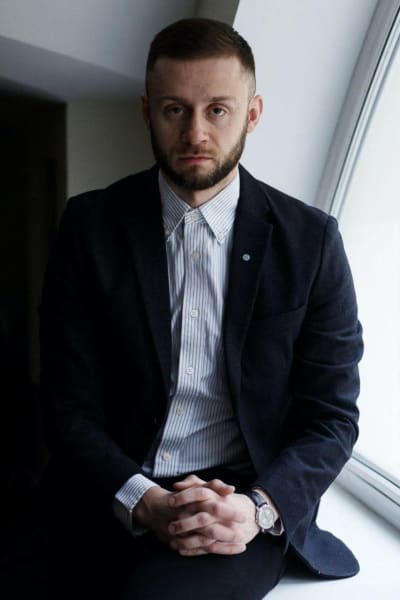 Epidemiologen Anton Bartjuk sitter på ett fönsterbräde med knäppta händer och ser in i kameran.