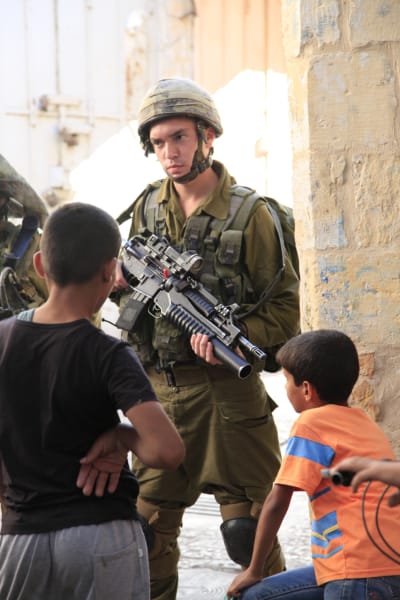 Israelisk soldat står vakt kring bosättare i Hebron