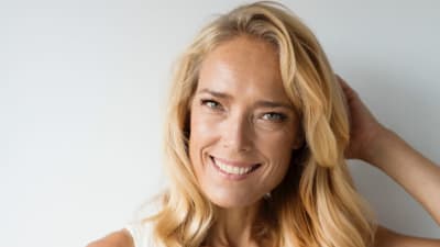 Tanssija Minna Tervamäki poseeraa kameralle hymyilevin kasvoin vasen käsi pään takana hiuksissa.