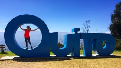 Kvinna poserar med stora bokstäver som stavar huvudstaden Quito.