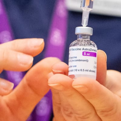 Lähikuva pienestä rokotepullosta, josta otetaan ruiskuun rokotetta. Pullon kyljessä näkyy teksti: "Vaccine AstraZeneca. 5 ml."