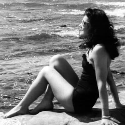 Nainen ottaa aurinkoa rannalla.