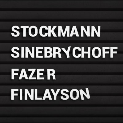 Mustassa nimitaulussa valkoisella nimet: Stockmann, Sinebrychoff, Fazer ja Finlayson.