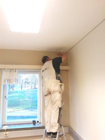Man i byggföretaget Se-Kas vita overall målar innervägg.