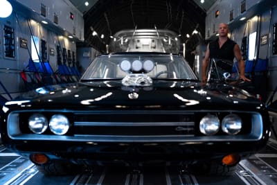 Vin Diesel står bredvid en svart bil.
