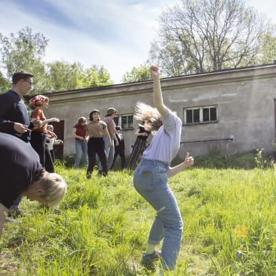 Människor dansar på en äng och i bakgrunden spelar en man musik.