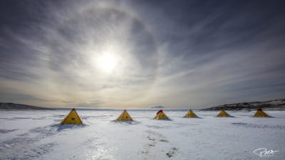 En låg sol över tält på isen i Antarktis. 