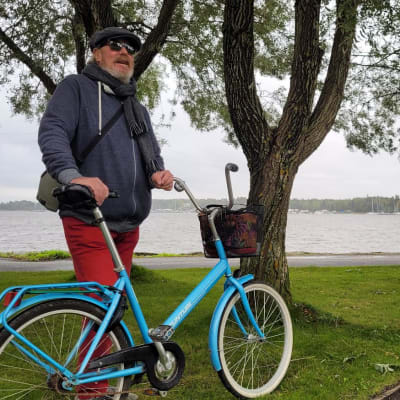 Mies seisoo polkupyöränsä kanssa rannan läheisessä puistossa Vaasassa