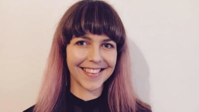 Porträtt av skribenten Salla med lila hår och leende.