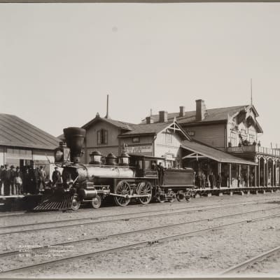 Gammal svartvit bild på järnvägsstation.
