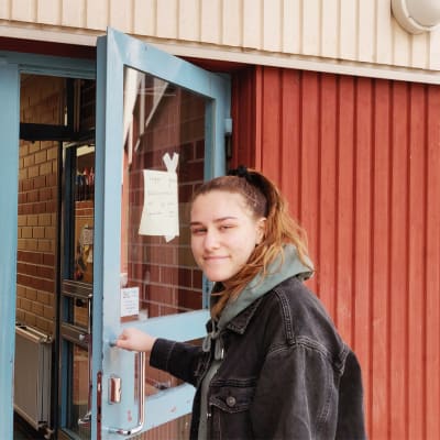 En ung kvinna öppnar en dörr. Till vänster synns en plansch där det framkommer att det här är en vallokal i Boxby skola.