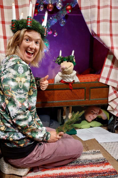 Lisa Gerkman och musen Lotus är klädda som lucior. Under sängen sticker dockföraren Stefanie af Björksten fram huvudet. 