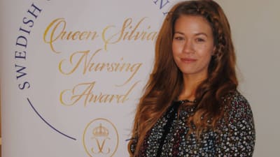 Maiju Björkqvist bredvid en skylt var det står Queen Silvia Nursing Award.