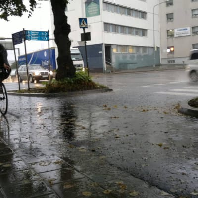 Cyklist iklädd regnkläder cyklar i kraftigt regn.