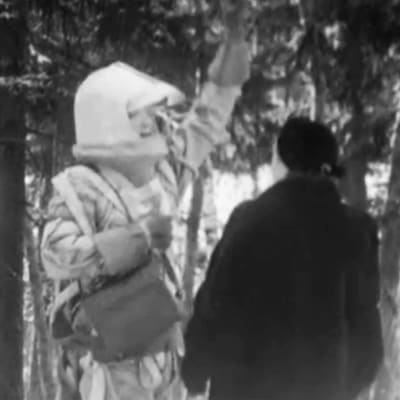 Avaruuspukuinen mies juttelee naisen kanssa kylänraitilla.