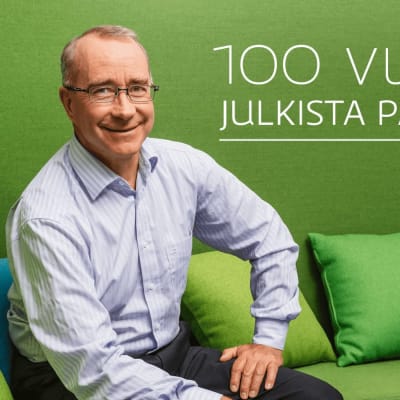 Ylen julkisen palvelun johtaja Ismo Silvo istuu vihreällä sohvalla. Kuvassa teksti 100 vuotta julkista palvelua.