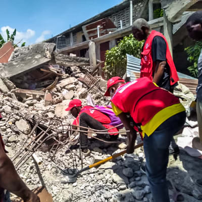 hjälparbetare gräver i rasmassor efter jordbävning