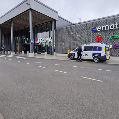 Poliisiauto on pysäköitynä Liisanlehdon Prisman edustalle. Vasemmalla puolella kuvaa kävelee myymälän työntekijä.
