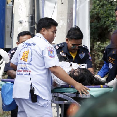 Medicinsk personal hjälper och flyttar på en skadad som ligger på en bår efter explosioner i Hua Hin, thailand.