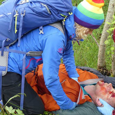 två personer i vildmarken hjälper en tredje som fått en skallskada, simulerd bild