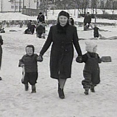 Äiti ja lapset puistossa.