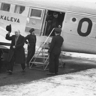 Aero Oy:n Junkers Ju 52/3m "Kalevan" (OH-ALL) matkustajia Helsingin lentoasemalla. Vasemmalla ylhäällä koneen siiven päälle kiivennyt starttipäällikkö, joka keskustelee ohjaamossa olevien lentäjien kanssa.