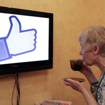 Bildcollage av äldre dam som tittar på en tv, där en Facebook-tumme visas. 