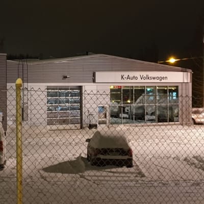 Hämeenlinnalaisen autokaupan K-Auton piha on lähikuvassa. Lumihanki, pihalla muutama auto. Liike on suljettu, koska ilta.