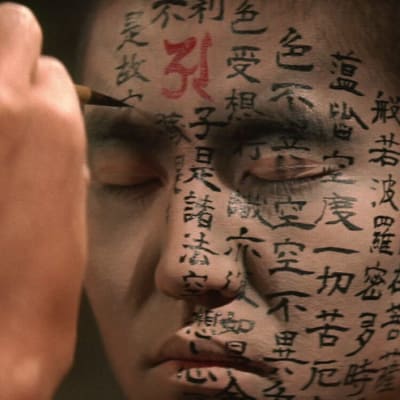 Munkin kasvoja koristellaan japanilaisella kirjoituksella. Kuva elokuvasta Kwaidan.