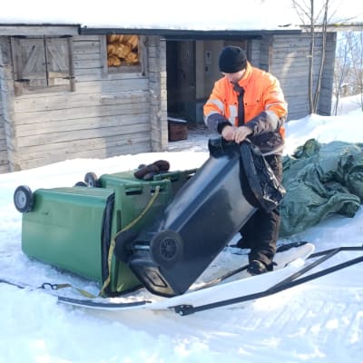Metsähallituksen Luontopalvelujen kenttämestari Sami Lapinniemi kuljettaa roskiksia pois Hannukurusta maaliskuussa 2023.