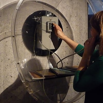 Nainen valitsee numeroa yleisöpuhelimessa Tampereen Rupriikki-museossa