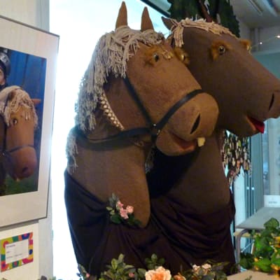 Kaksi keppihevosta sekä valokuva hevosesta ja ritarista Lastenkulttuurikeskus Rullan näyttelyssä. 