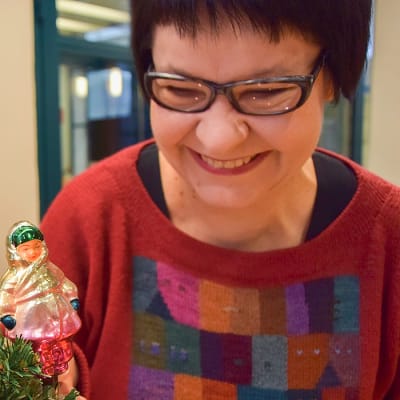 Taja Filatov katsoo naista kuvaavaa joulukoristetta kuusenoksalla