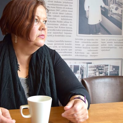 Nainen istuu kahvilassa ja katsoo ikkunasta ulos