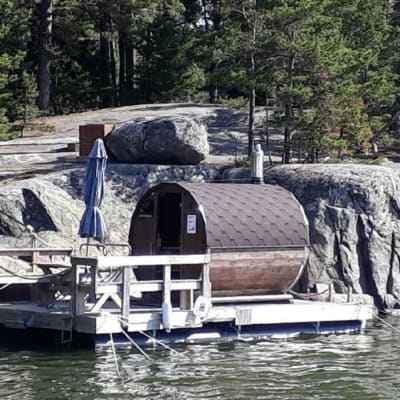 En bastu på en brygga utanför klippor vid en holme. 